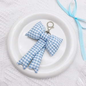 Detailed close-up of blue and white checkered fabric bow keychain with silver lobster clasp
