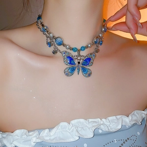 Détail d'un collier multicouche avec pendentif papillon bleu et perles fantaisie