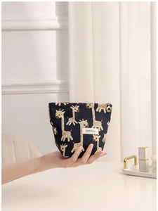Navy blue giraffe jacquard makeup bag with cute floral zipper pull shown held by hand
