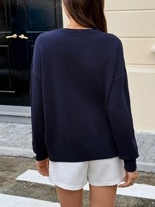 Navy blue long sleeve knit sweater for women with white shorts, back view on a casual street