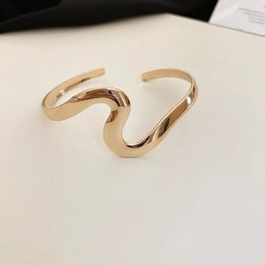 Detailed view of a gold wavy open bangle showing smooth polished metallic texture