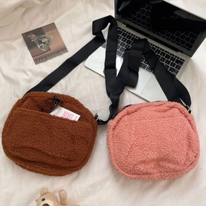 Detail of plush lamb wool crossbody bags in brown and pink with adjustable straps