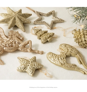 Décorations de Noël dorées à paillettes avec étoiles et ailes sur un fond blanc pelucheux