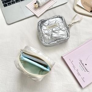 Detail of silver and white heart-quilted PU pouches with smooth metallic finish and zippers