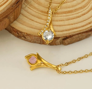 Detailed view of gold plated necklaces with zircon pendants on a rustic wooden stand