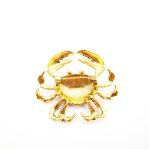 Detailed top view of gold crab brooch showing alloy texture and pin mechanism on white background