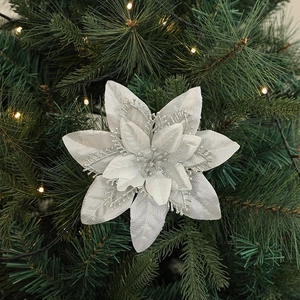 Sparkling silver artificial poinsettia flower decoration on a lit Christmas tree