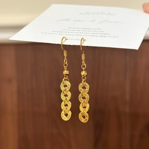 Macro shot of gold tassel earrings with interlinked rings on a wooden surface