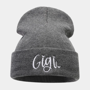 Close-up of gray knit beanie featuring white Gigi script embroidery on the folded cuff