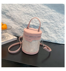 Close-up of pink and beige bucket bag featuring textured fabric and leather handles