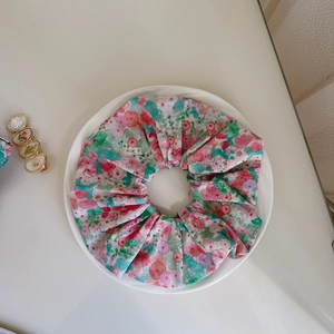 Detailed macro view of a pink floral cotton hair scrunchie on a white ceramic plate
