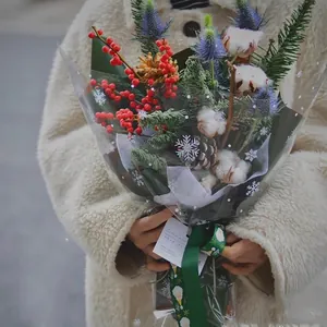 Winter bouquet with pine cones and red berries in snowflake pattern cellophane wrapping