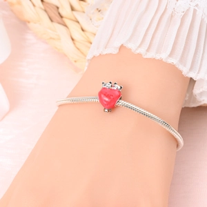 Detail of silver-plated snake chain bracelet featuring a red heart pendant with cute charms