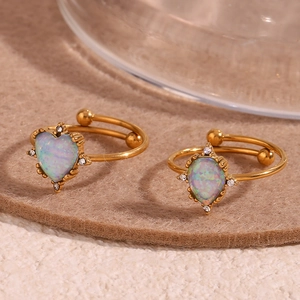 Macro shot of 18K gold plated heart opal rings with zircon accents on beige felt
