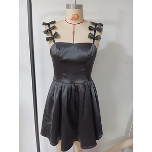 Détail d'une robe de soirée en satin noir avec bretelles à nœuds et jupe plissée courte