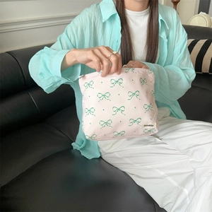 Detailed view of pink floral storage bag with green bow patterns held by a model