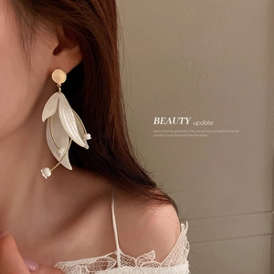 Elegante Ohrringe mit weißen Blütenblättern und Goldakzenten an einem Model