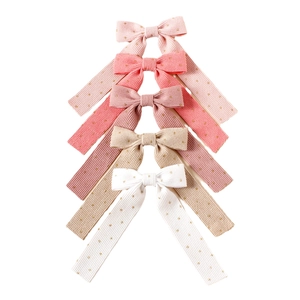 Vertical stack of corduroy bow hair clips with gold foil dots in five assorted pastel colors