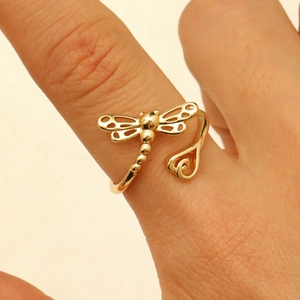 Detail eines goldenen Libellen- und Herzrings, in einer Nahaufnahme am Finger gezeigt