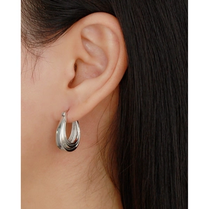 Nahaufnahme eleganter mehrlagiger Silber-Creolen an einem weiblichen Model für einen schicken Look