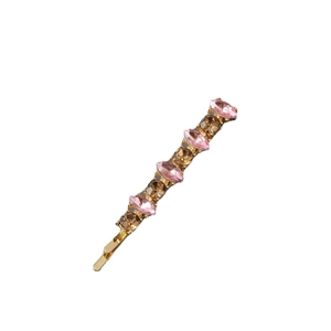 Close-up of gold metal hair clip with alternating pink and brown sparkling rhinestones