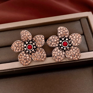 Detail of vintage floral earrings with champagne crystals and red core bead on silk background