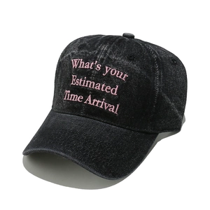 Close-up of pink 'Estimated Time Arrival' embroidery on washed grey denim baseball cap
