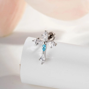 Silver cross stud earring with blue and clear rhombus cubic zirconia on a soft pink background