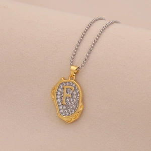 Detail of golden letter F pendant with crystals on a delicate silver bead chain