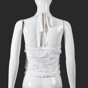 Macro shot of white halter crop top featuring intricate 3D floral pleated texture detail