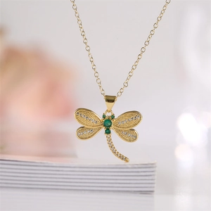 Macro d'un pendentif libellule doré avec zircone verte et des ailes évidées détaillées