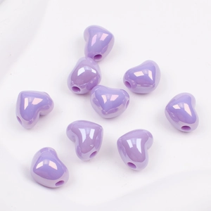 Macro shot of purple heart-shaped beads with a pearlescent finish for DIY jewelry crafting