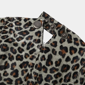 Macro detail of leopard print PU cap showing metallic snap buttons and textured fabric finish
