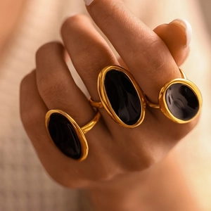 Three gold PVD coated stainless steel rings with oval black enamel on female hands
