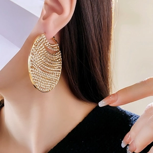 Gros plan d'une boucle d'oreille chaîne dorée sertie de zircons sur un mannequin femme