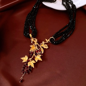 Detail of vintage necklace with gold leaf design and red beads on brown silk fabric
