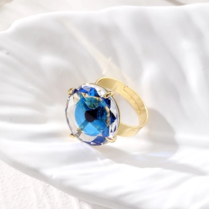 Luxury gold adjustable ring with a large blue round faceted crystal on ceramic tray
