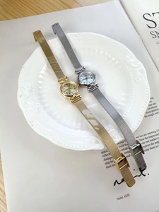 Detail of vintage gold and silver mesh strap women's watches on a decorative white plate