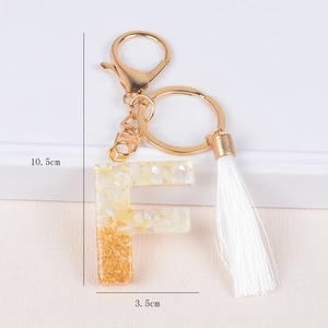 Detailed view of resin letter F keychain with gold foil, white stone, and measurements