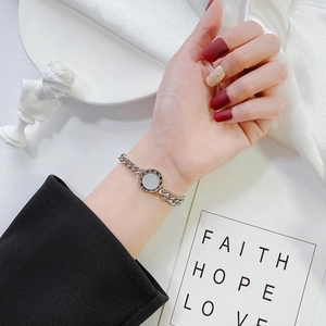 Silver chunky chain bracelet with roman numeral round pendant on an elegant silk fabric