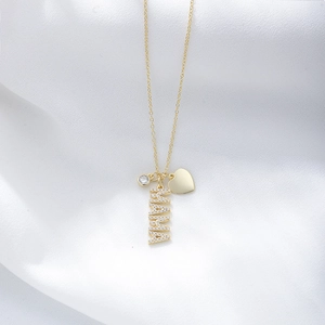 Close-up of golden MAMA pendant necklace with sparkling diamonds on silk background