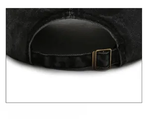 Close-up of adjustable bronze metal buckle and washed denim strap on black baseball cap