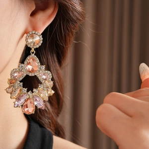 Vue détaillée de boucles d'oreilles dorées avec pierres roses et strass sur un mannequin