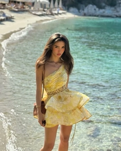 Detail of yellow floral one-shoulder dress featuring waist cut-out and ruffled hemline