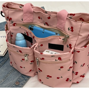 Pink cherry print tote bag showing multiple pockets with phone and spray bottle storage