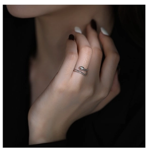 Macro shot of silver snake ring featuring green gemstone eyes on a model's finger