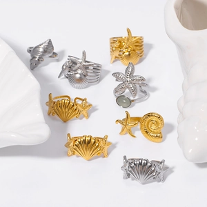 Gold and silver stainless steel starfish rings with seashell charms on white background