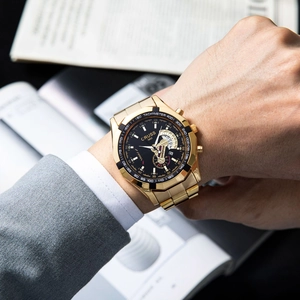 Close-up of gold quartz watch with black dial and luminous hands on a businessman's wrist