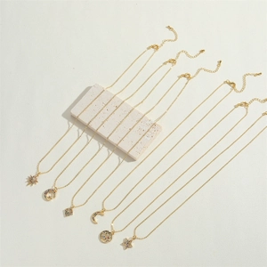 Close-up of gold star and moon necklaces with colorful zircons on white stone