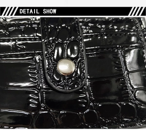 Close-up of black crocodile embossed leather texture with a silver metal buckle detail